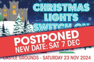 Christmas lights switch on graphic with a red banner across saying postponed and the new date in white writing