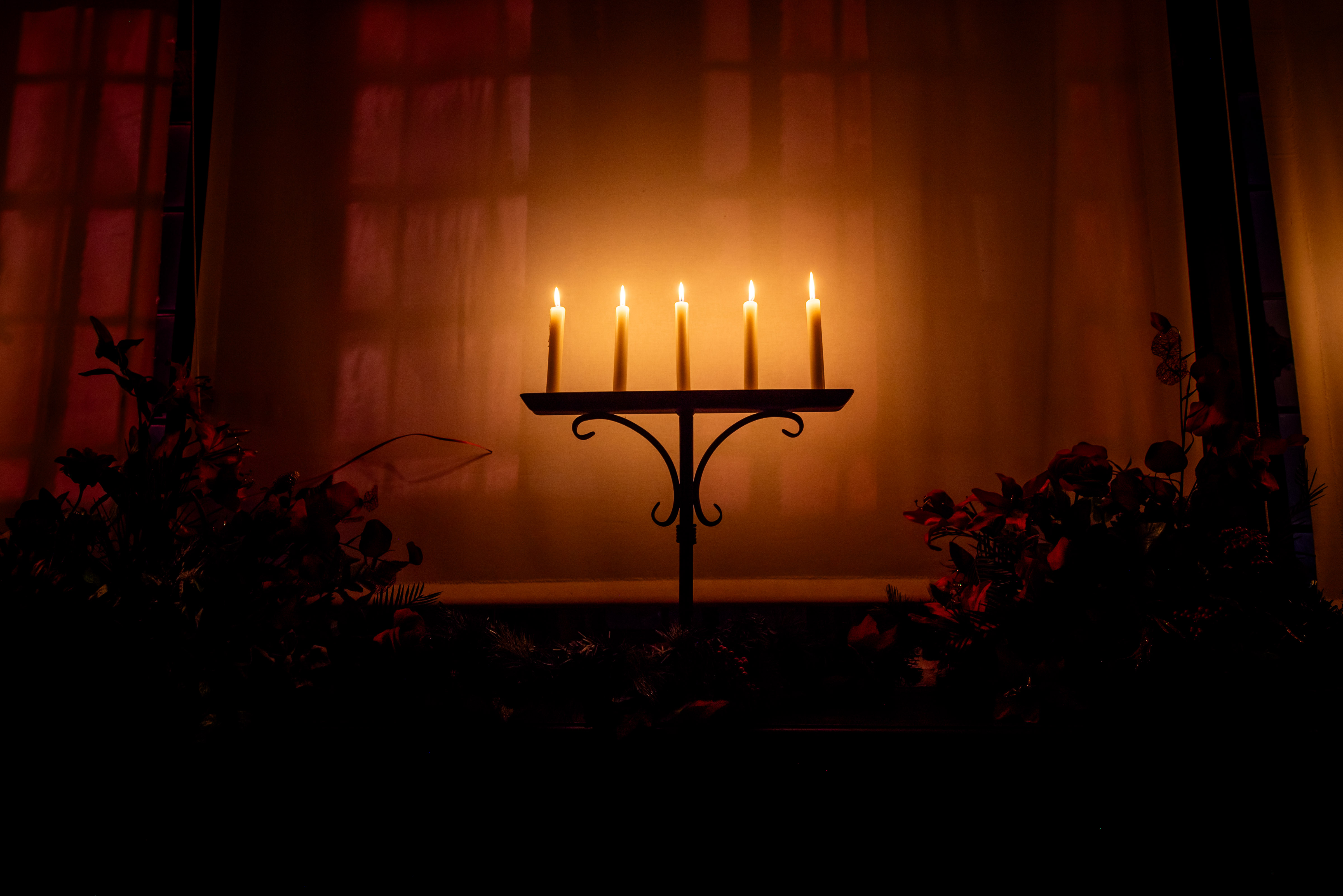 Photo of 5 pillar candles glowing against a castle wall