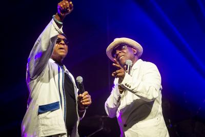 photo of the two people in the band Real thing, wearing white suits and singing 